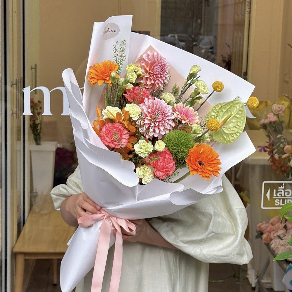 ช่อดอกไม้สีสันสดใสที่จัดเสร็จแล้ว วางบนโต๊ะร้านมีสุข